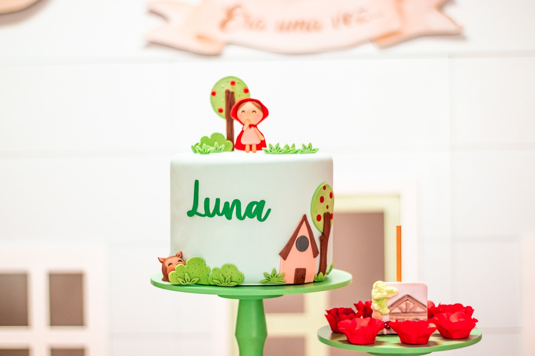Parte da decoração do aniversário de 1 ano da Luna mostrando o bolo fake e alguns doces