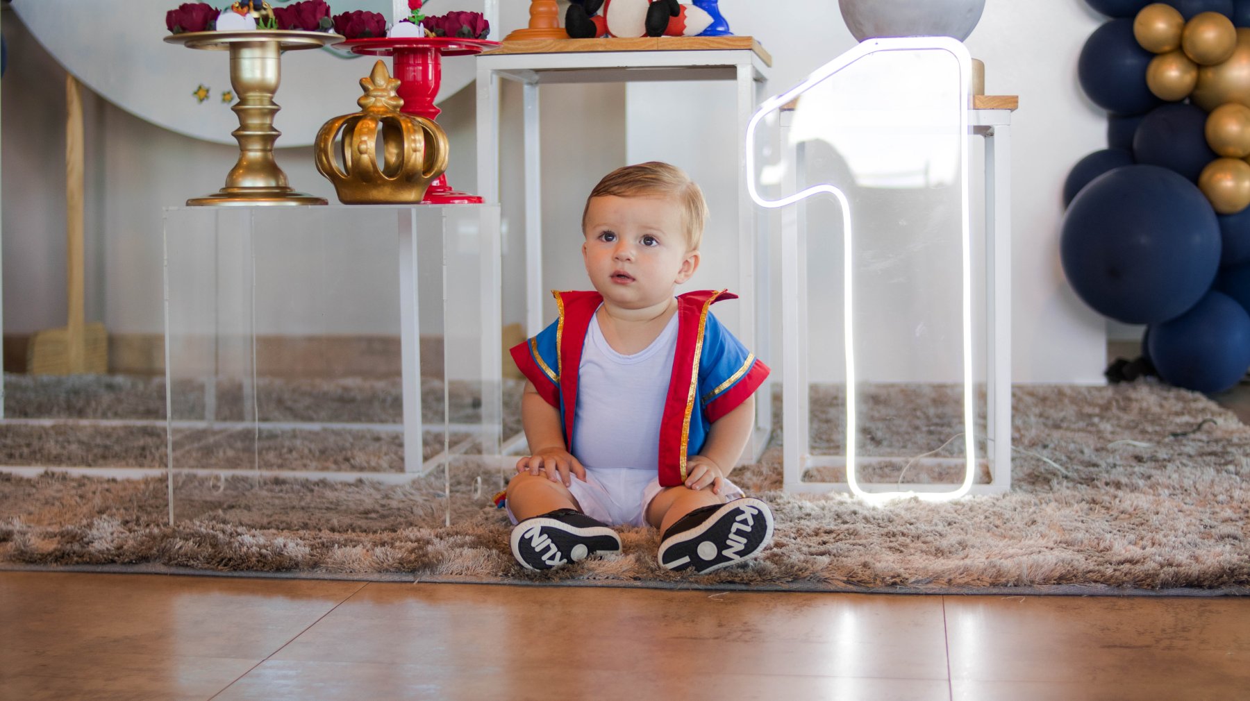 Pedrinho sentado em frente a decoração do aniversário dele